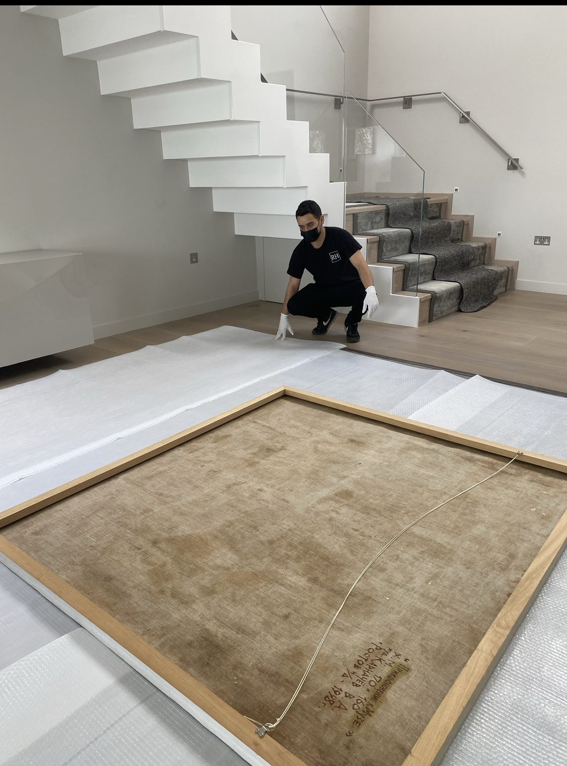 RH team member framing and protecting a rug in a modern home
