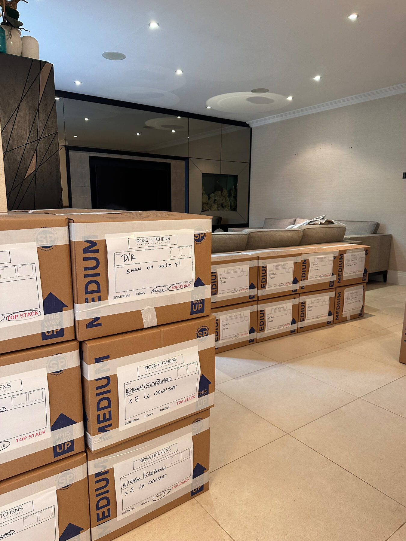 Packed and labelled RH cartons stacked in a living room