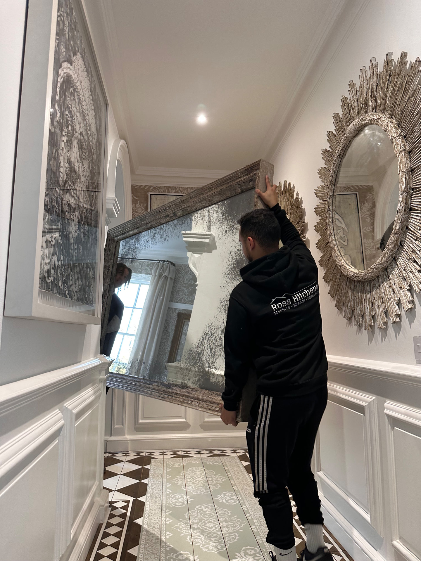 RH team member carrying a large antique mirror through a hallway
