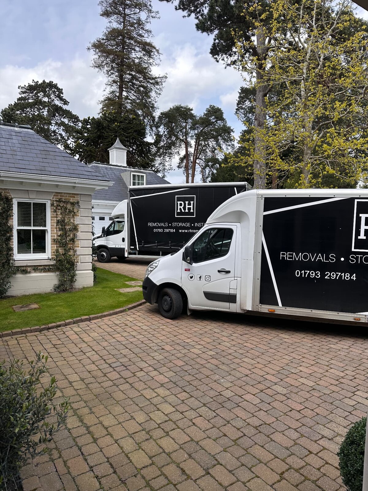 Two RH removal vehicles on the drive of a large house