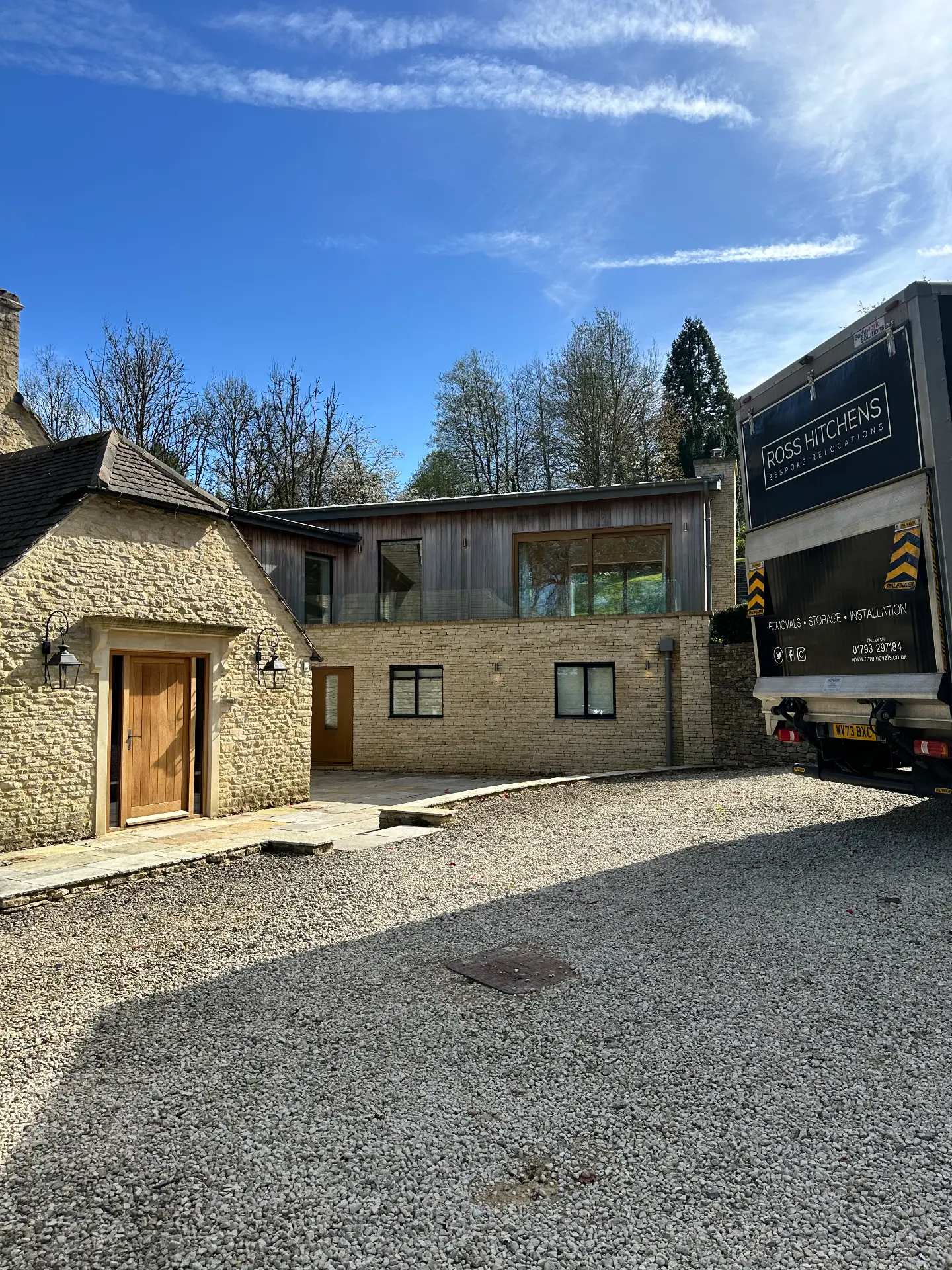 RH removal lorry on the gravel drive of a Cotswold stone and timber house