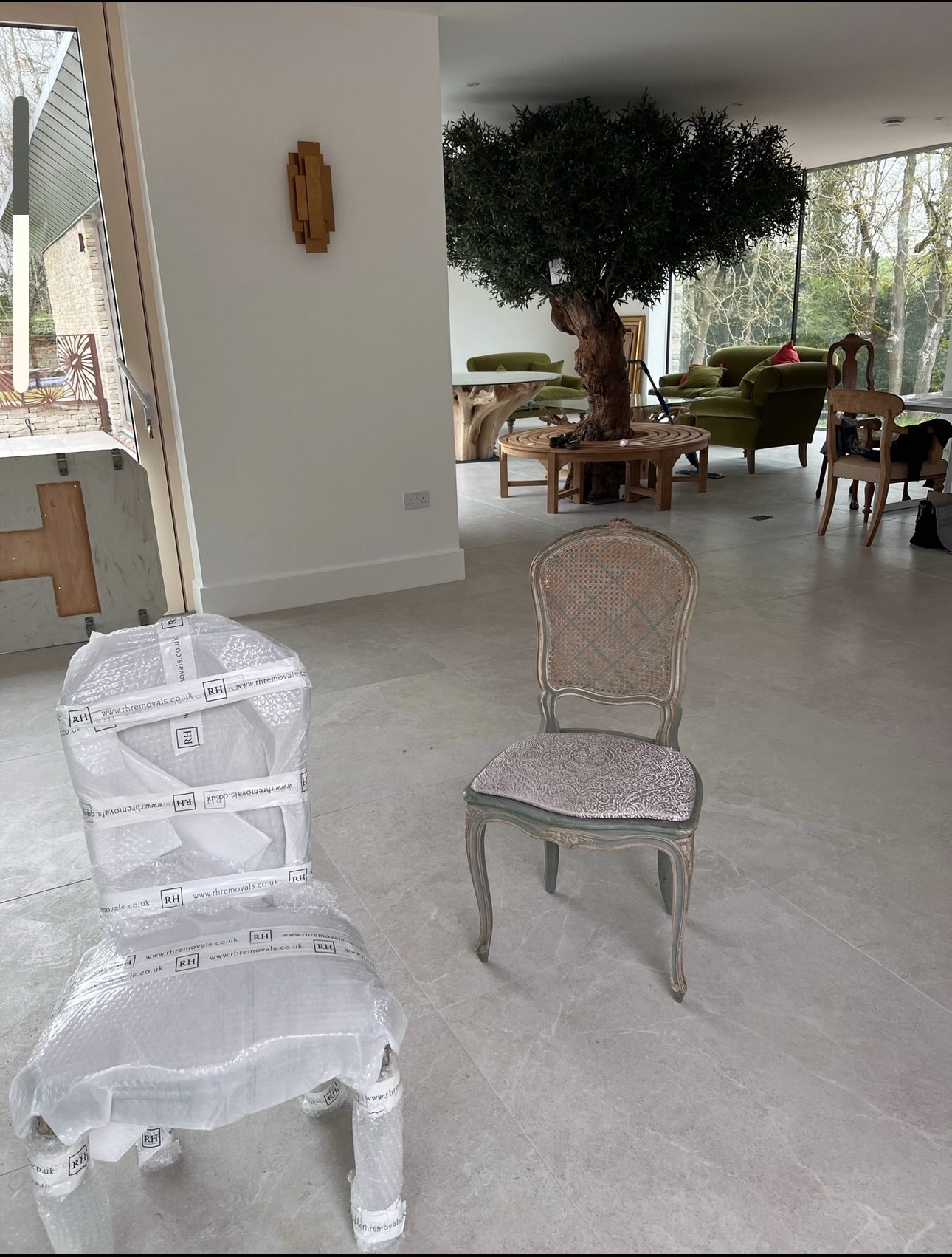 A dining chair wrapped in protective film beside an unwrapped chair