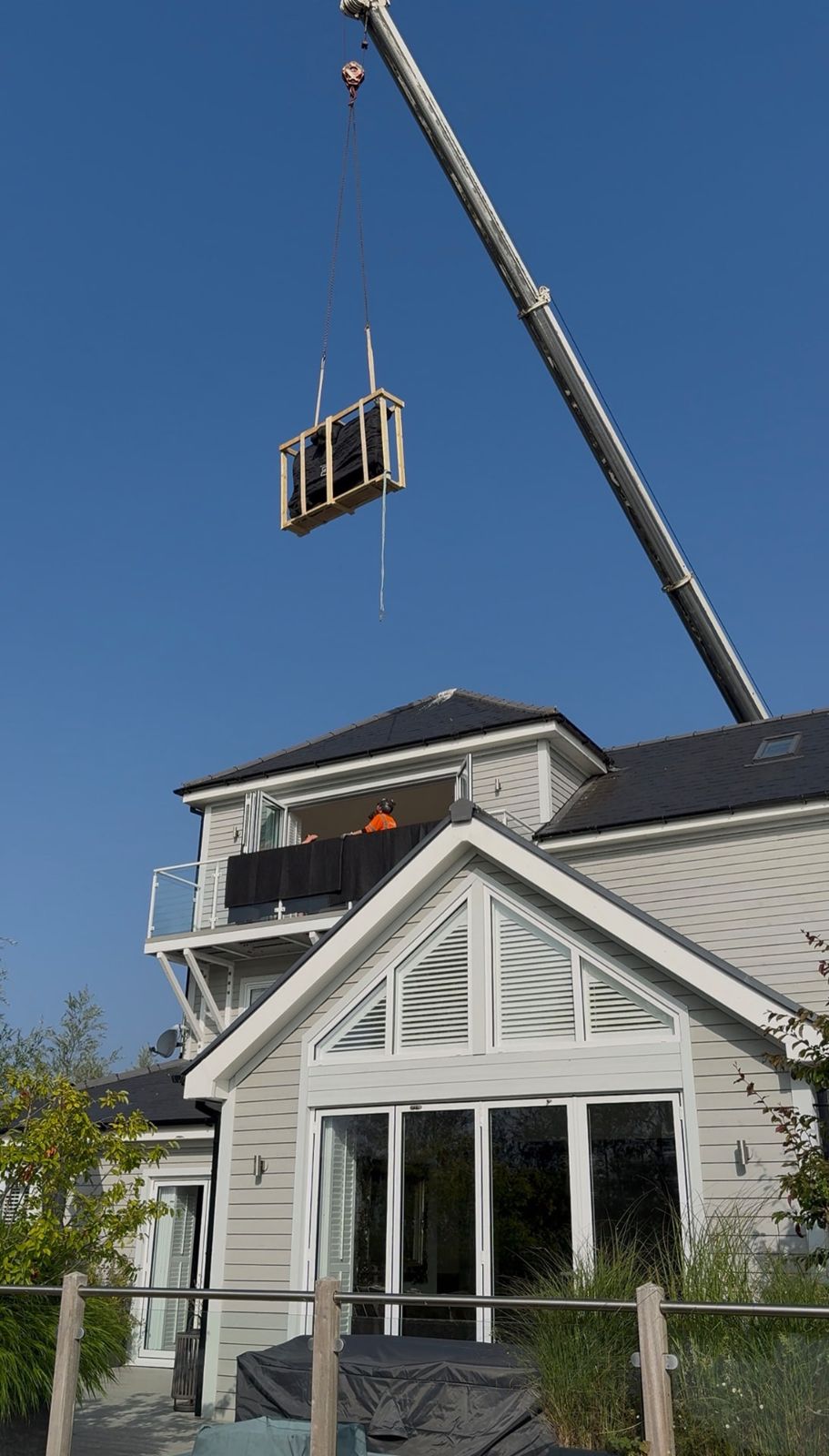Crane lifting a crated item to the balcony of a house during an RH move